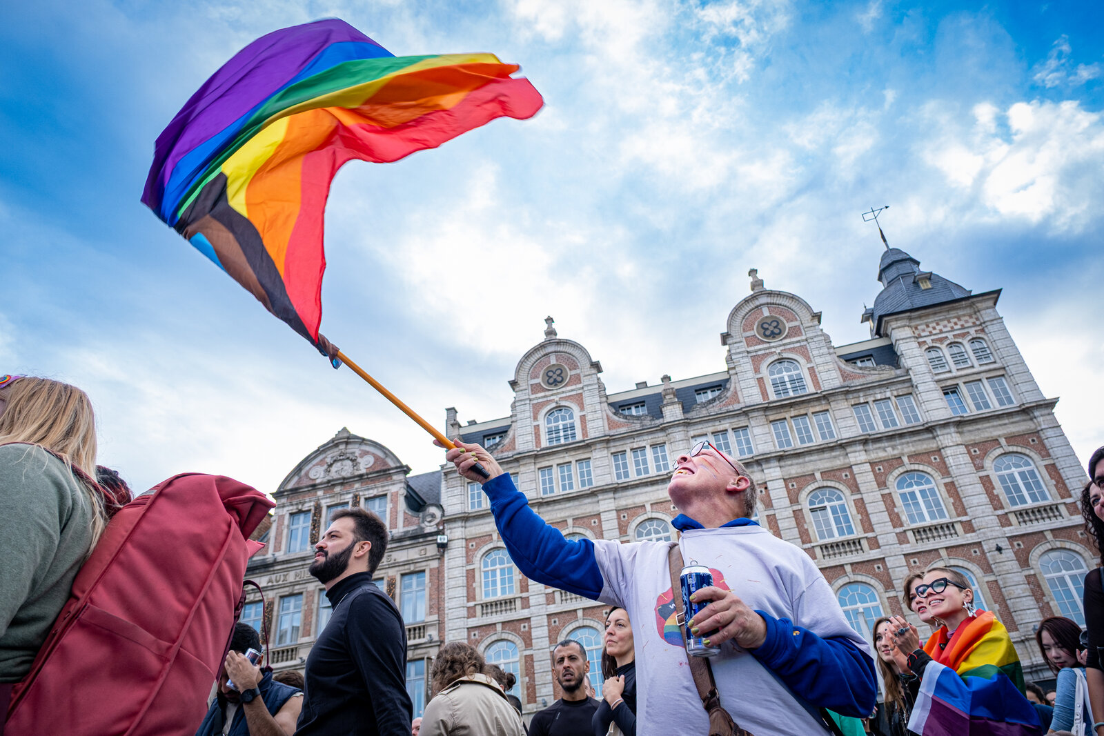 A rainbow flag goes up over the heads of the crowd. Leuven Pride 2025, photo: Bart Claes