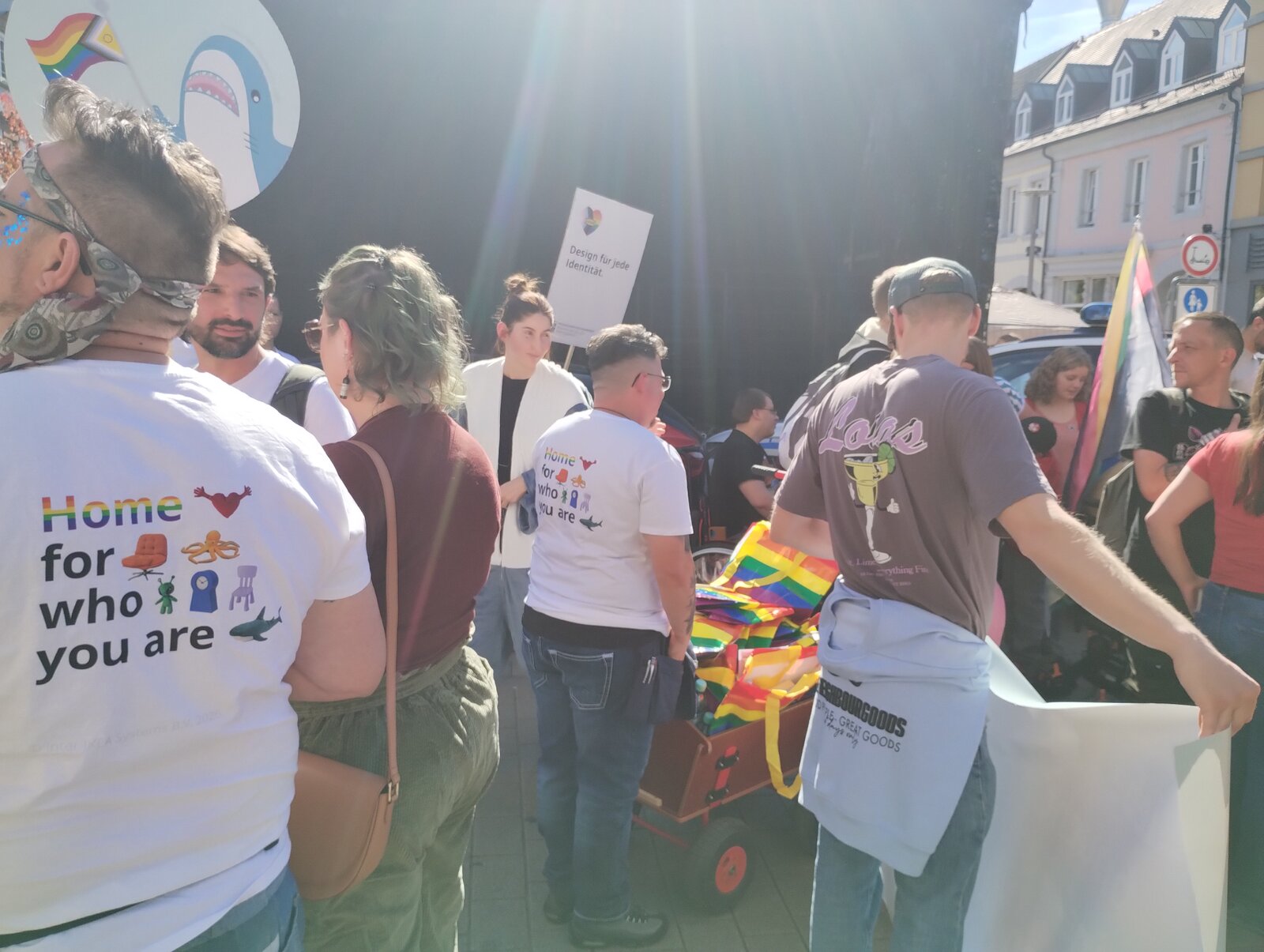 Volunteers in "Home for who you are" shirts beside a handcart loaded with flags. CSD Lautre 2026, photo: gaycation.eu