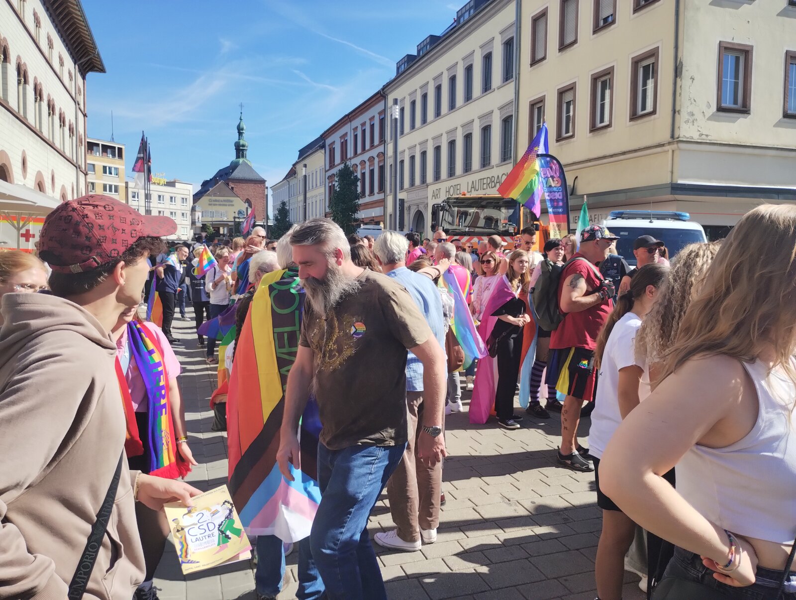 Pride and trans flags in the street in front of the Art Hotel Lauterbach, with a church tower at the end. CSD Lautre 2026, photo: gaycation.eu