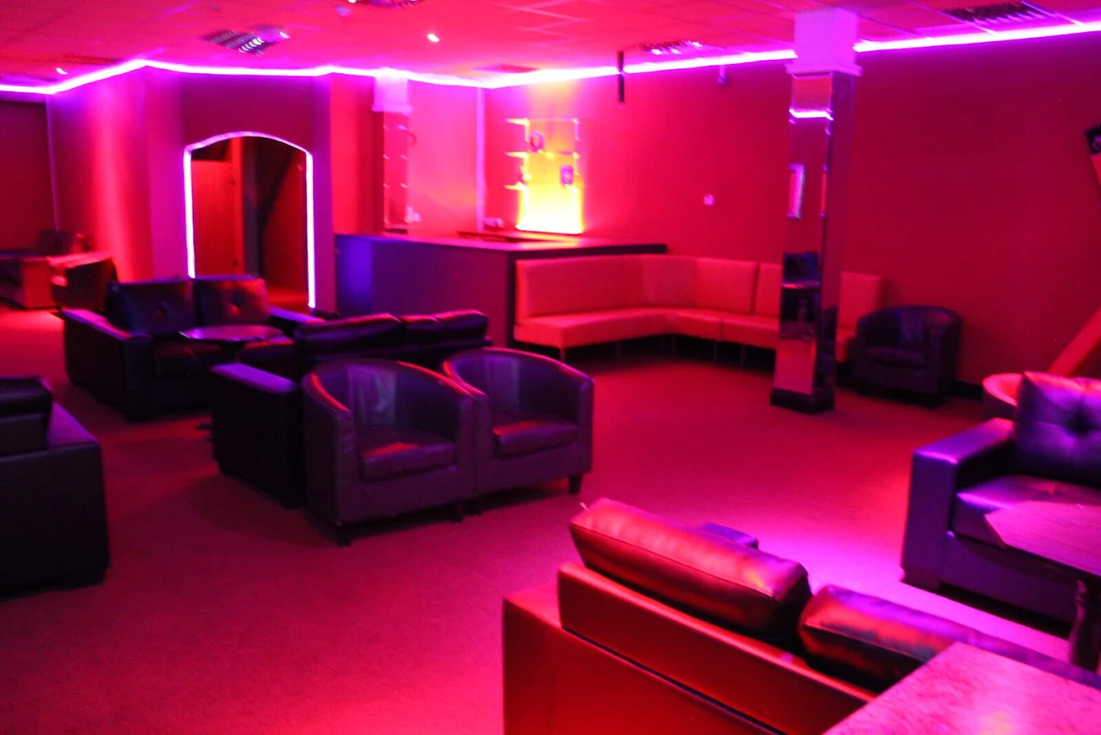 Spacious lounge area with black leather armchairs and a corner sofa arranged around the room
