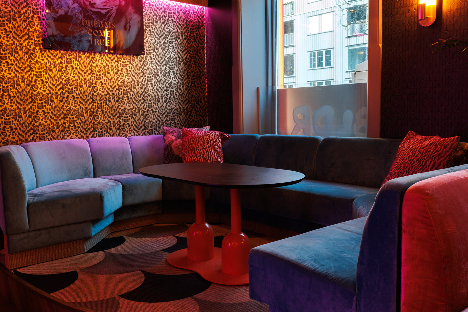 A velvet corner booth by the window, against a leopard-print wall with a Dreams Come True picture