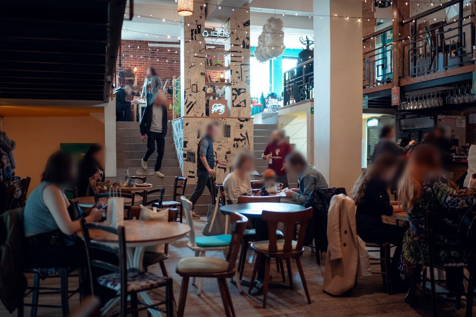The multi-level interior on a busy evening, staircase and bar in view.