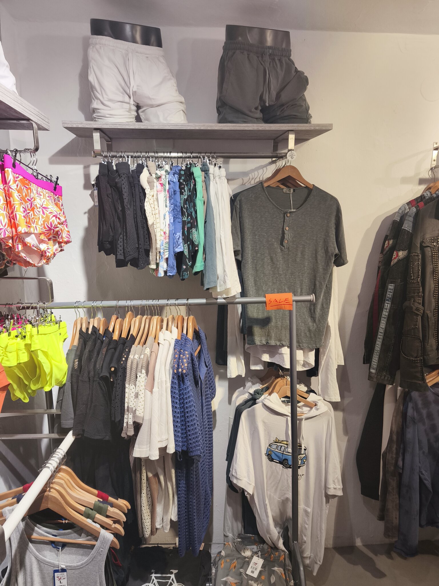 Vests and light tops on the rails, swim shorts on the shelf above and a sale tag on the green henley.