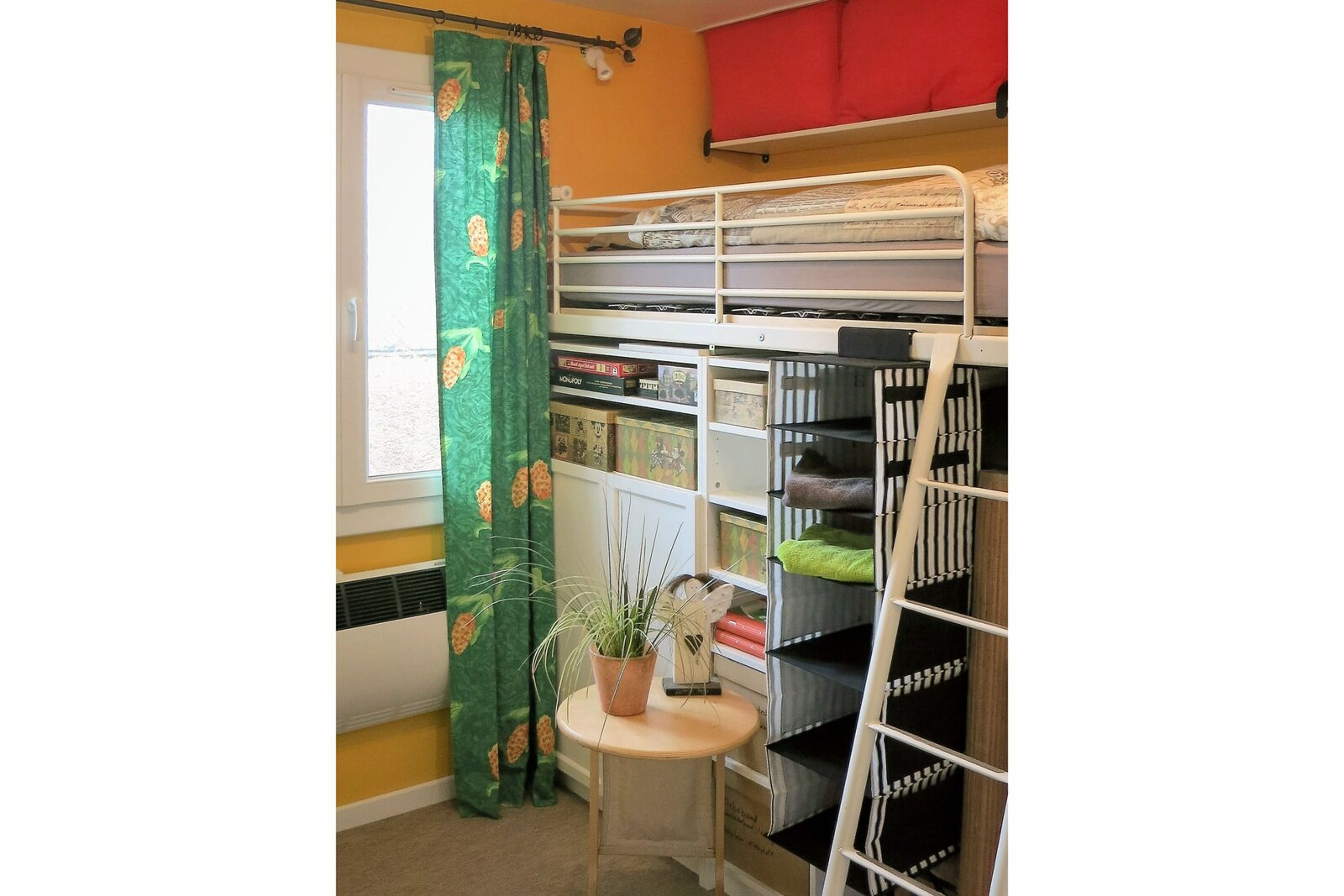 The single room, with a loft bed above shelves and a ladder up to it