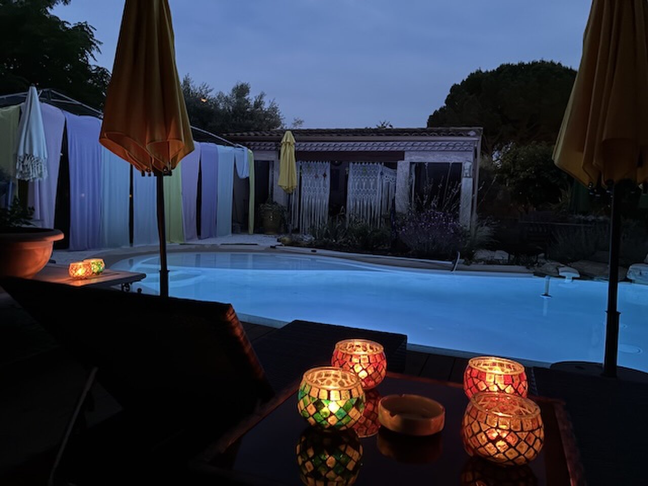 The pool lit up at dusk, with mosaic tealights glowing on the poolside table.