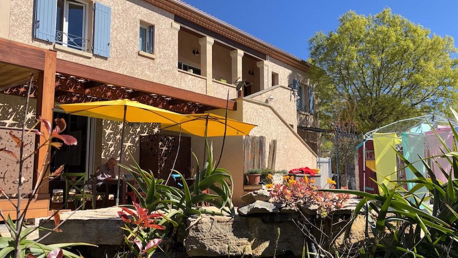 The terrace of the main house, under a pergola with a star-cut screen and a yellow parasol.