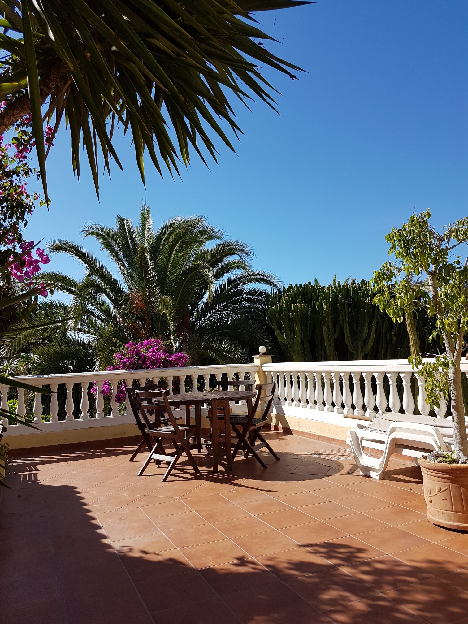 The guest terrace, with a table in the shade and loungers along the balustrade