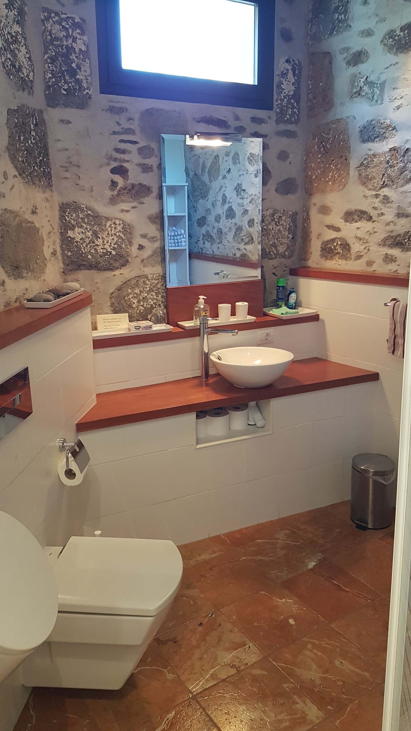 En suite bathroom, with a bowl basin on dark wood and the old stone left exposed