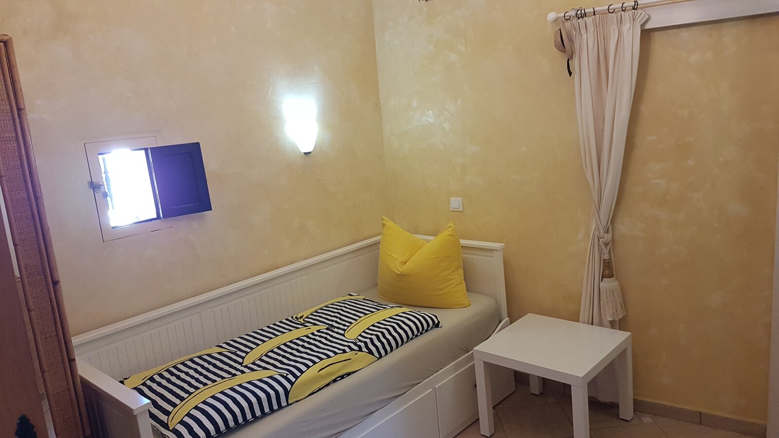 The small bedroom, in ochre plaster with a shuttered window