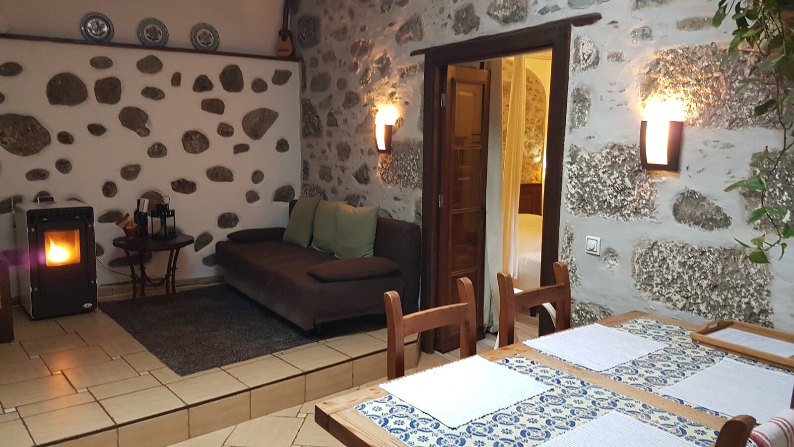 The sitting area with a pellet stove, laid out for dinner in front of the stone wall