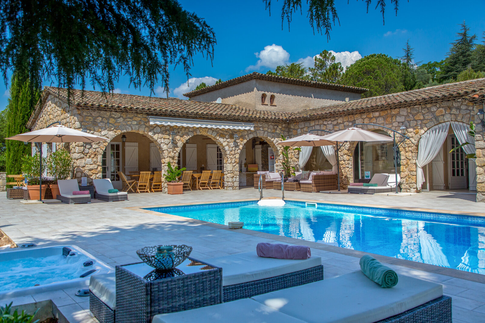 The pool terrace with a hot tub and lounge seating.