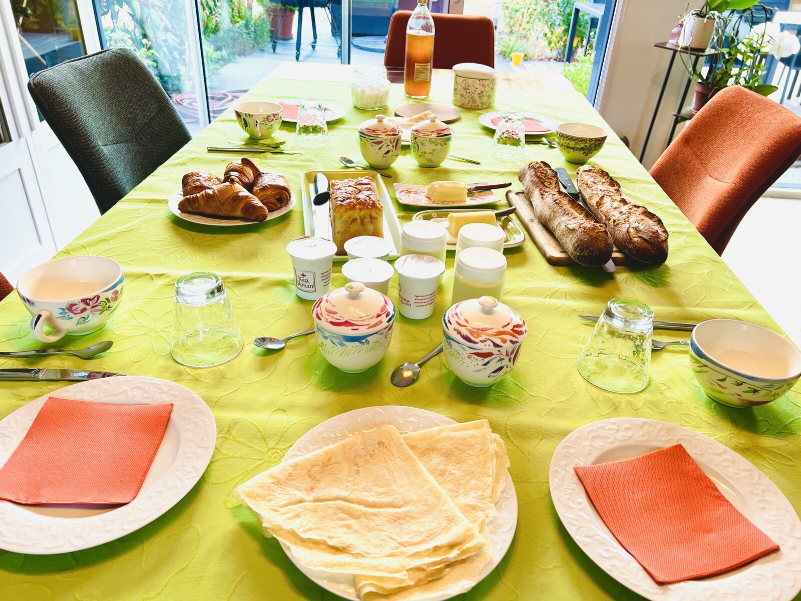 The breakfast table, set with croissants, homemade cake, baguettes and jam.