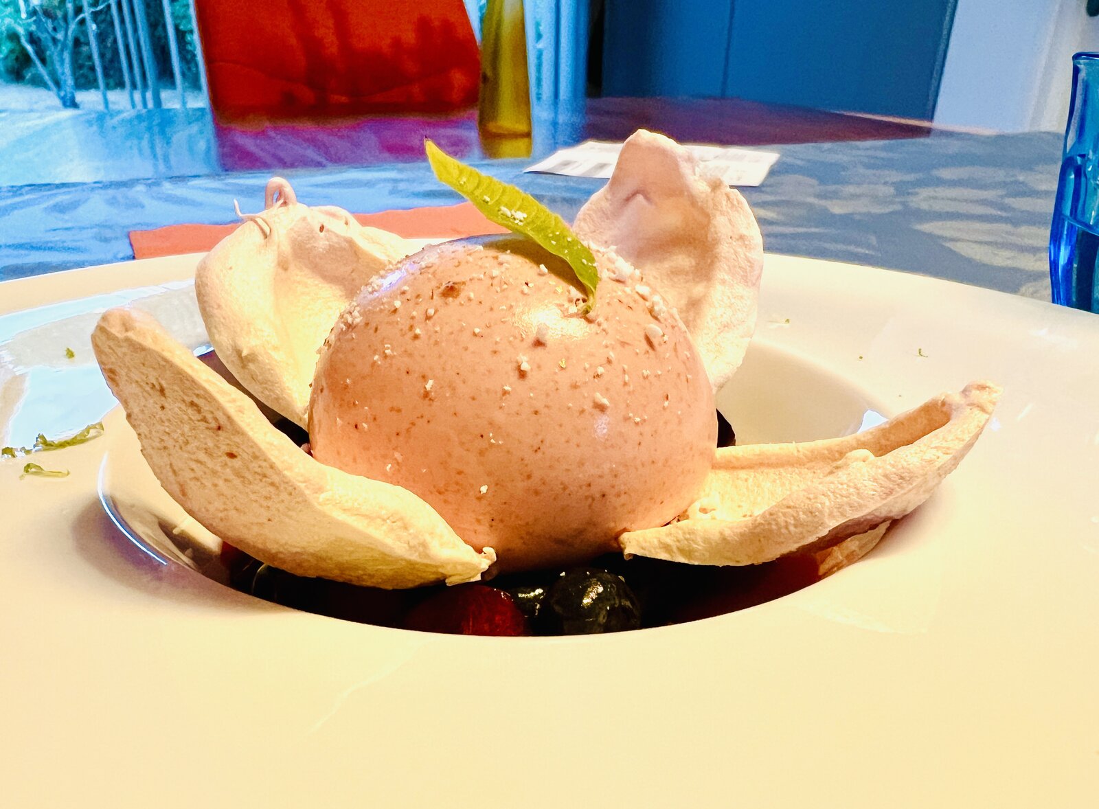 A meringue dessert with berries, served at a set table.