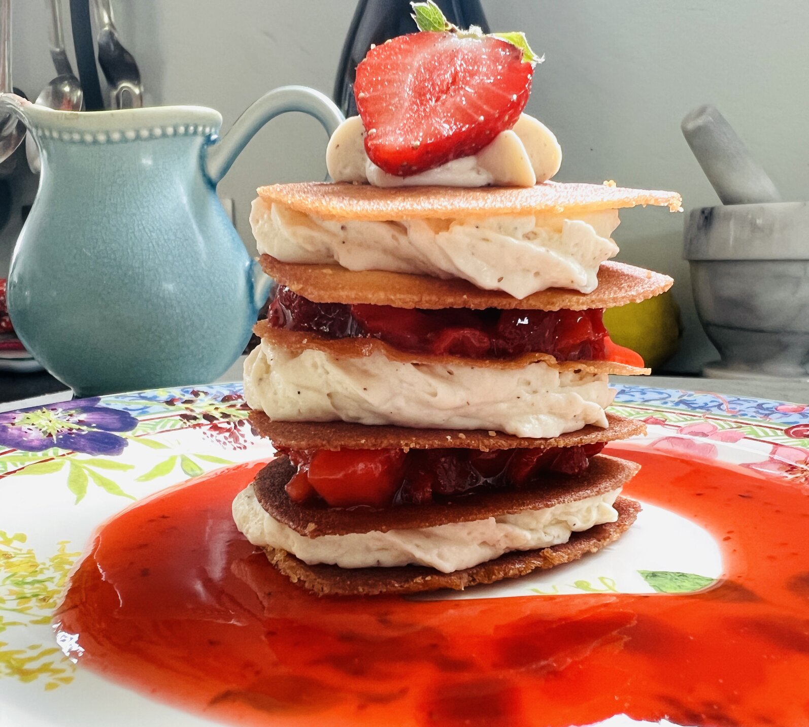 A stacked crepe dessert with vanilla cream and strawberries.
