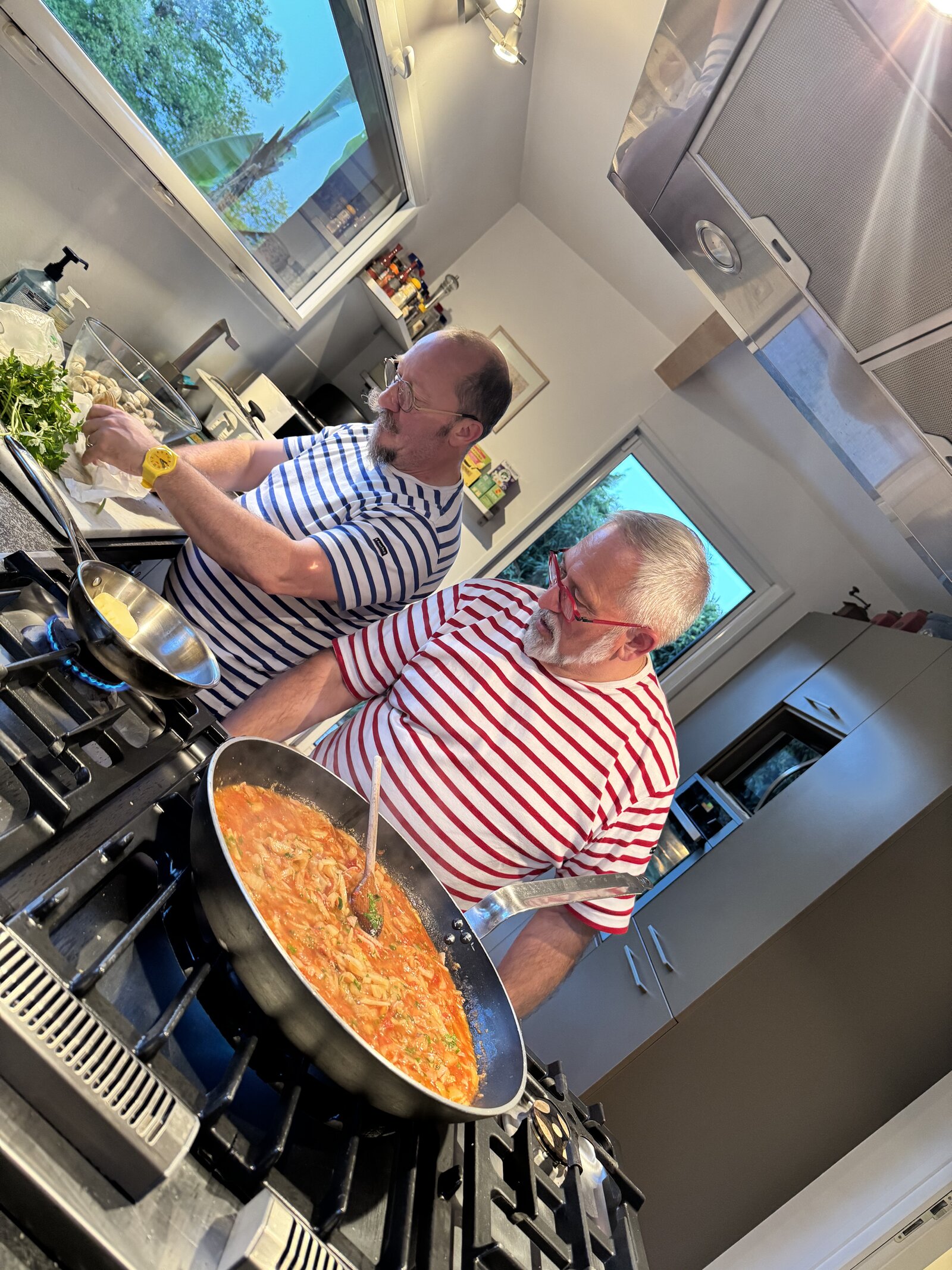 The two hosts cooking together in the kitchen.