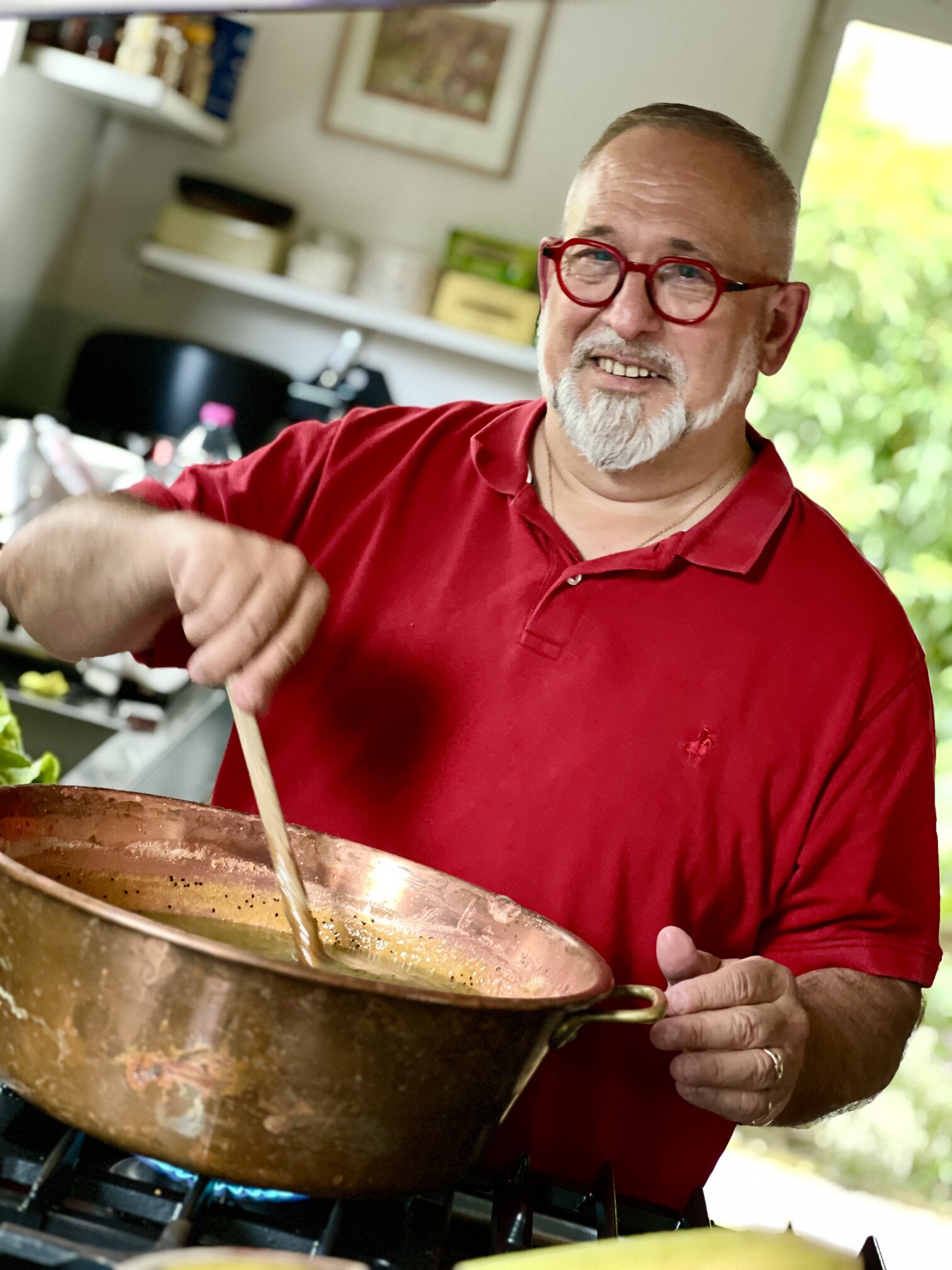 One of the hosts stirring jam in a copper pan.
