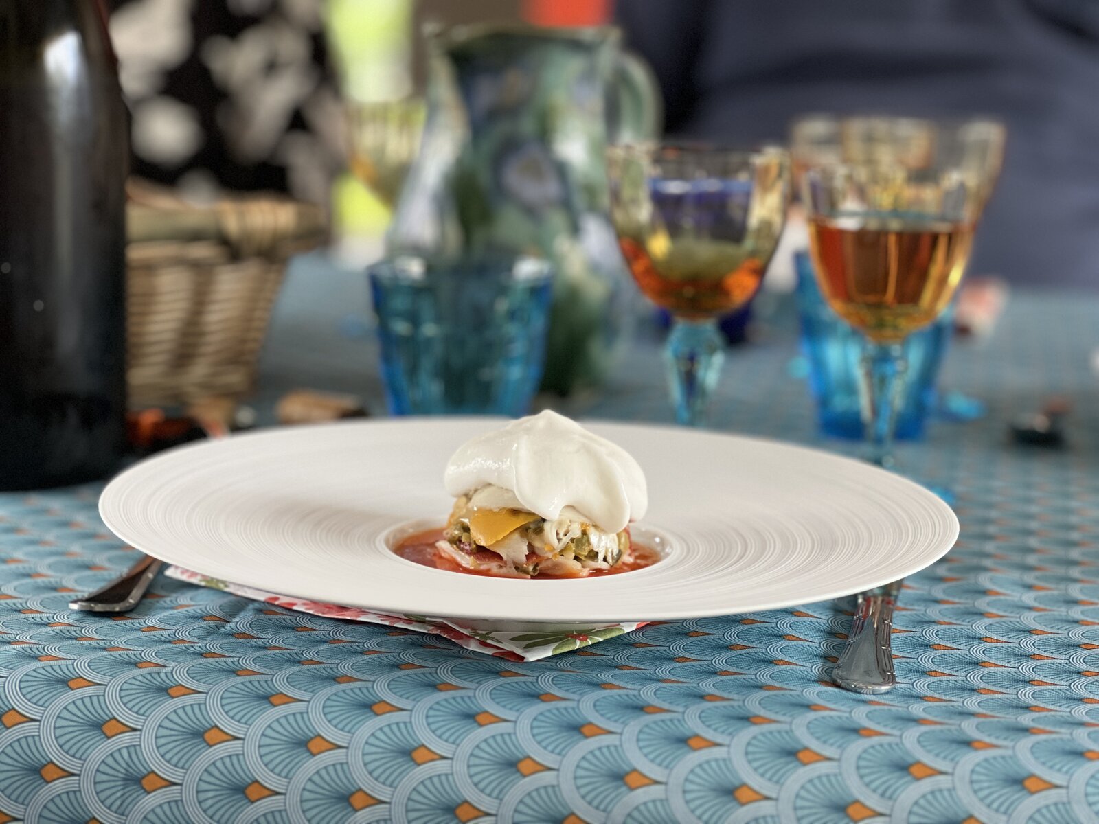 A small plated dish topped with cream, on a set table.