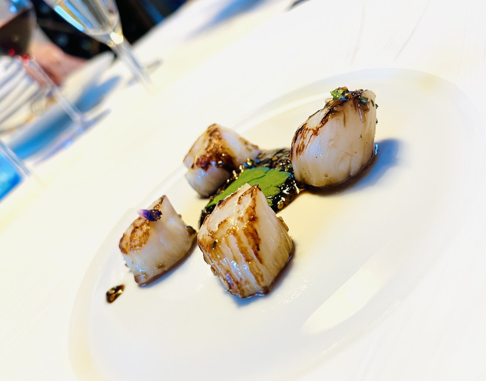 Four seared scallops on a plate.