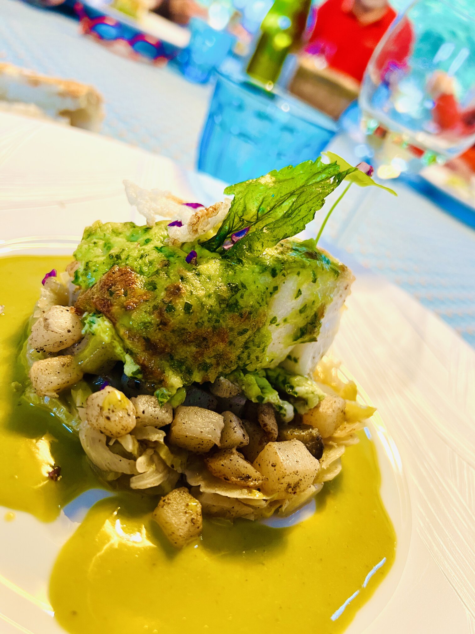 A herb-crusted fish fillet on scallops and vegetables.