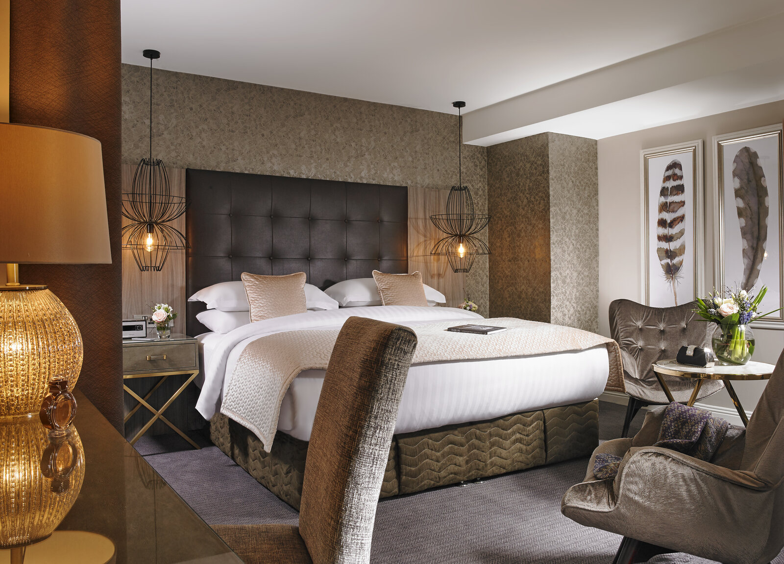Bedroom in the Shaw Suite, with a tufted headboard and hanging cage lamps.