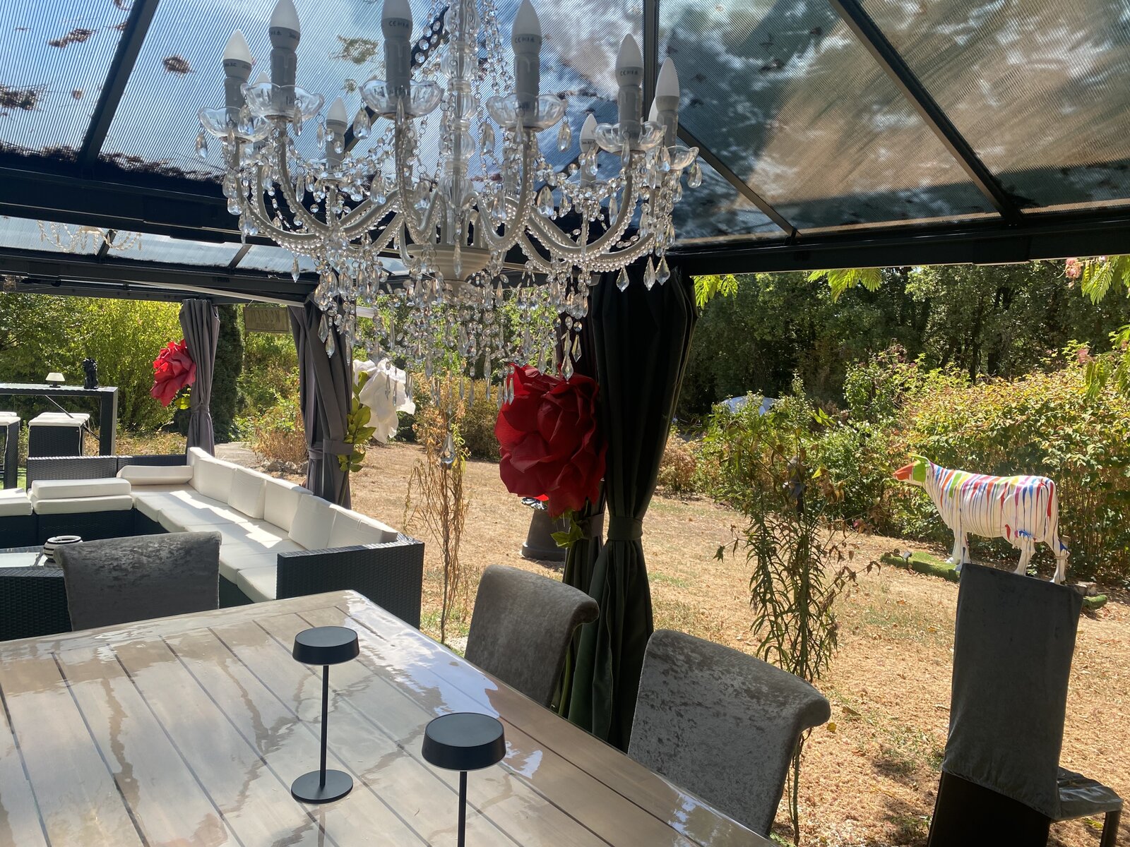 Covered dining area with a chandelier, overlooking the garden.