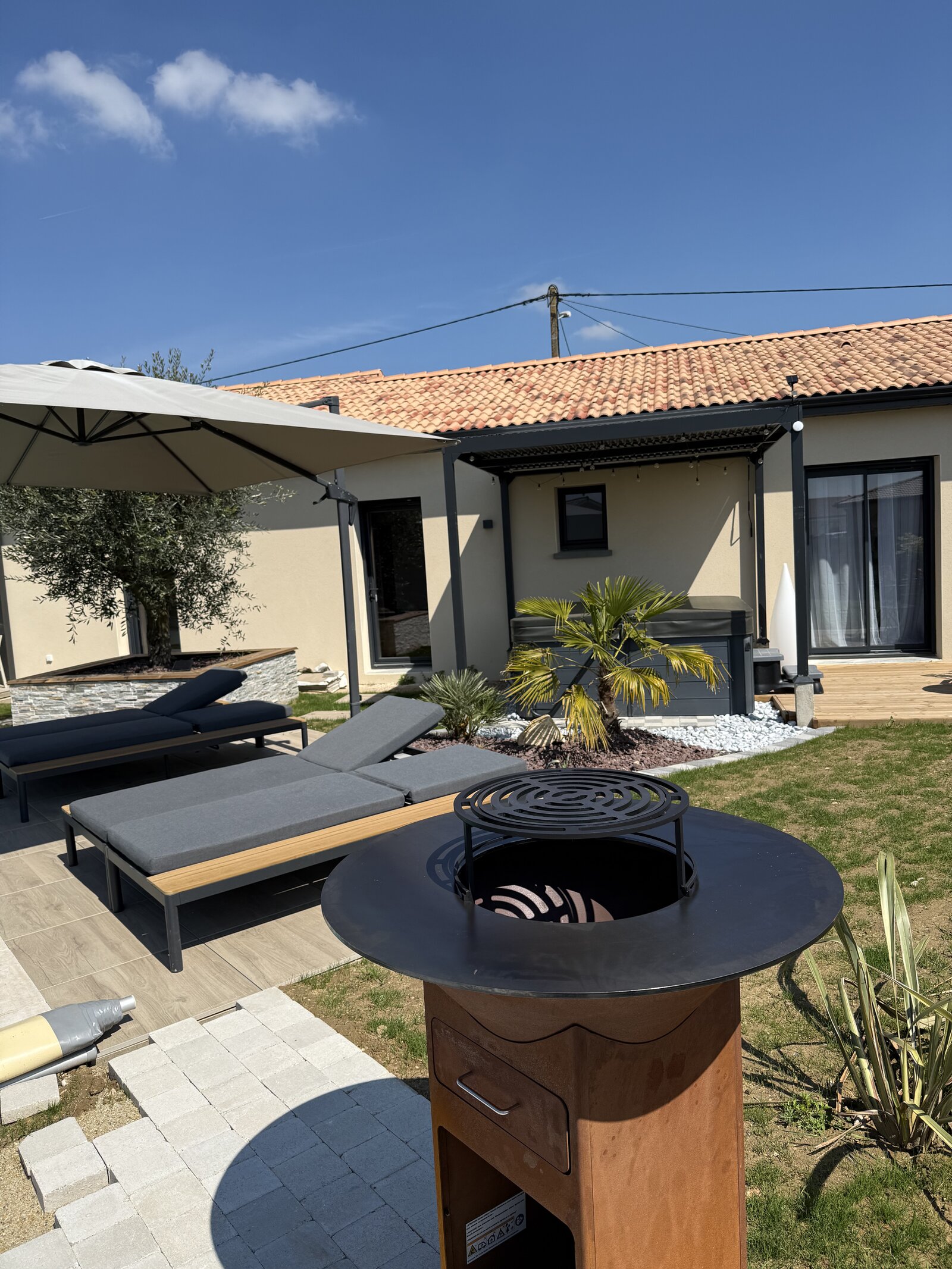 The fire pit and lounge seating in the garden, with the pool terrace behind.