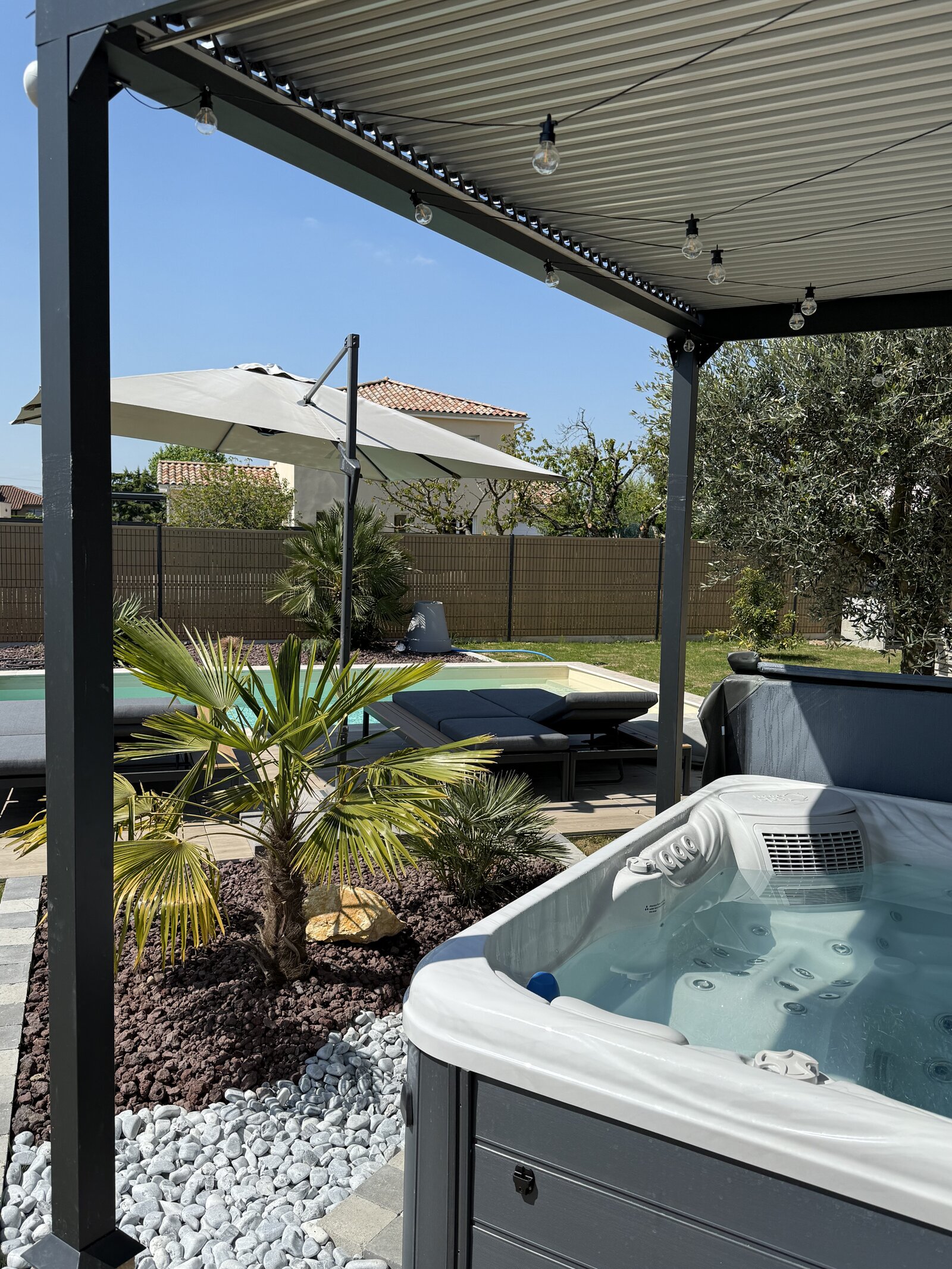 The covered terrace with hot tub, pool and garden view.