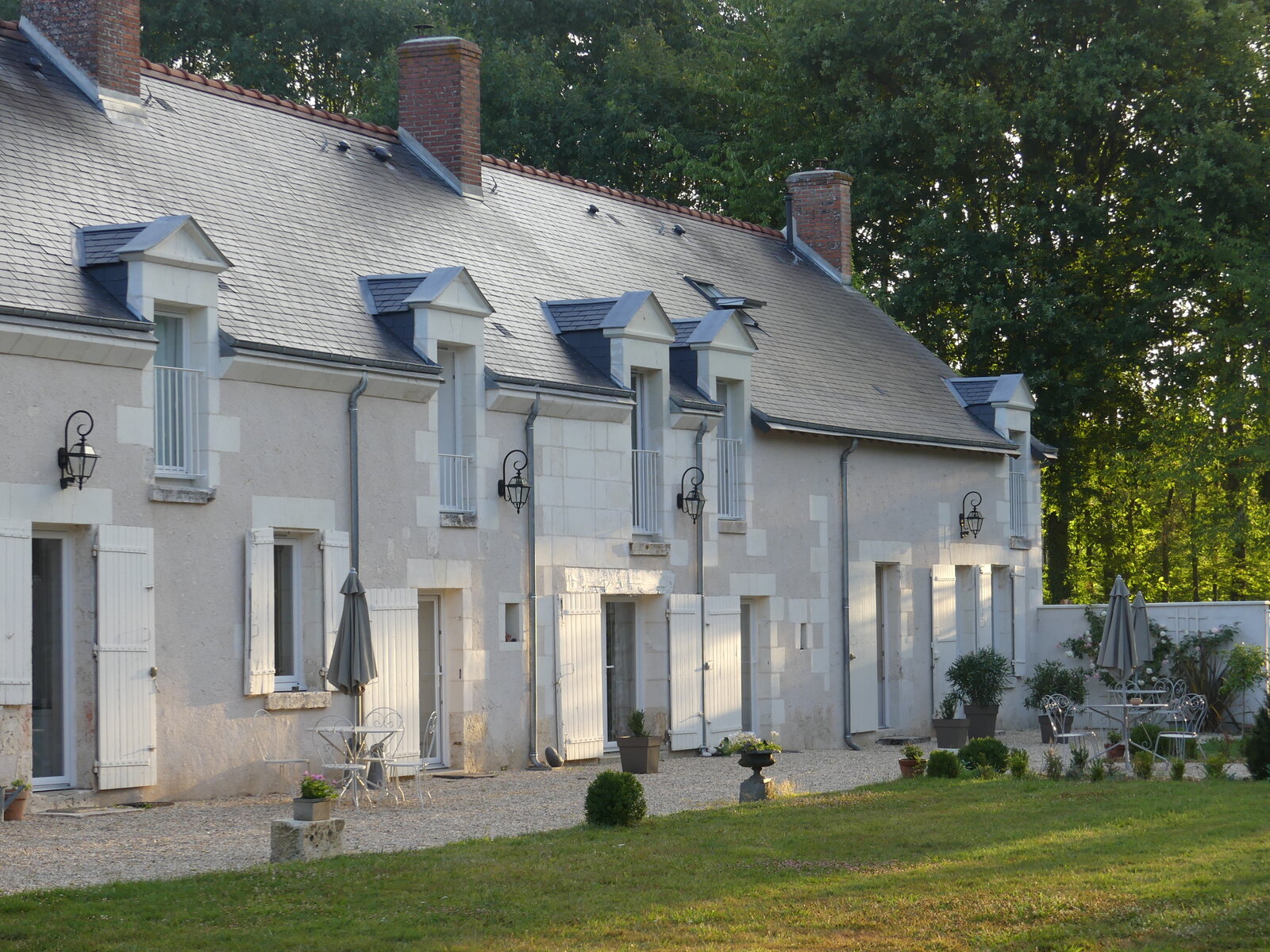 The longère seen from the gravel courtyard, with its dormer windows and outdoor seating.