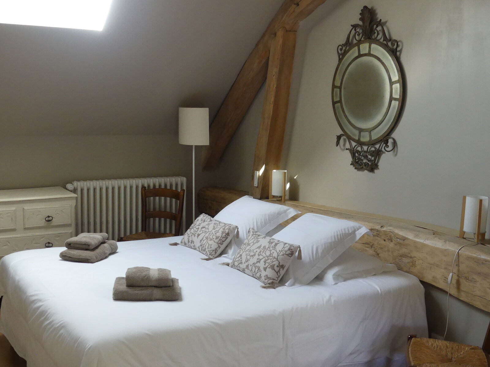 One of the guest rooms, set under the roof beams with a round mirror above the bed.