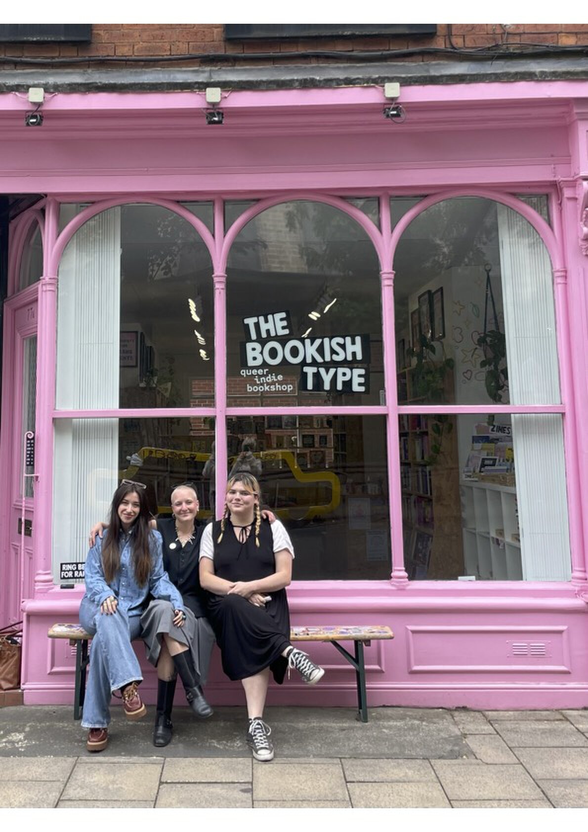 Three members of the team on the bench outside The Bookish Type's pink shopfront.