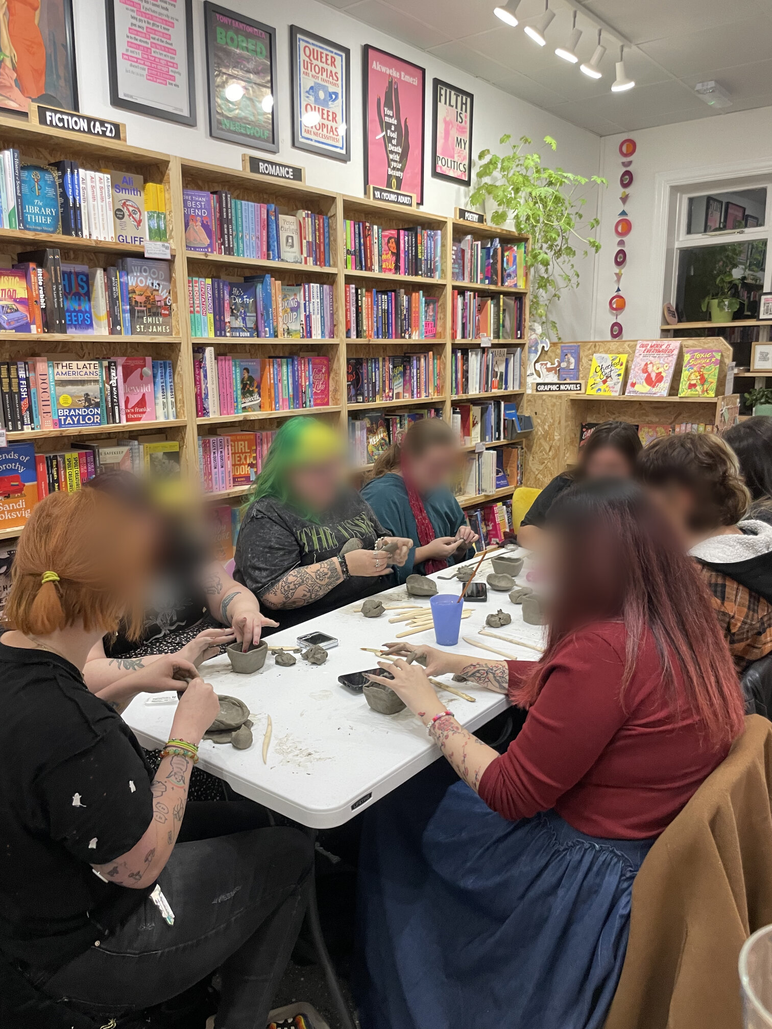 Visitors shaping clay at a pottery workshop held among the shop's fiction shelves.