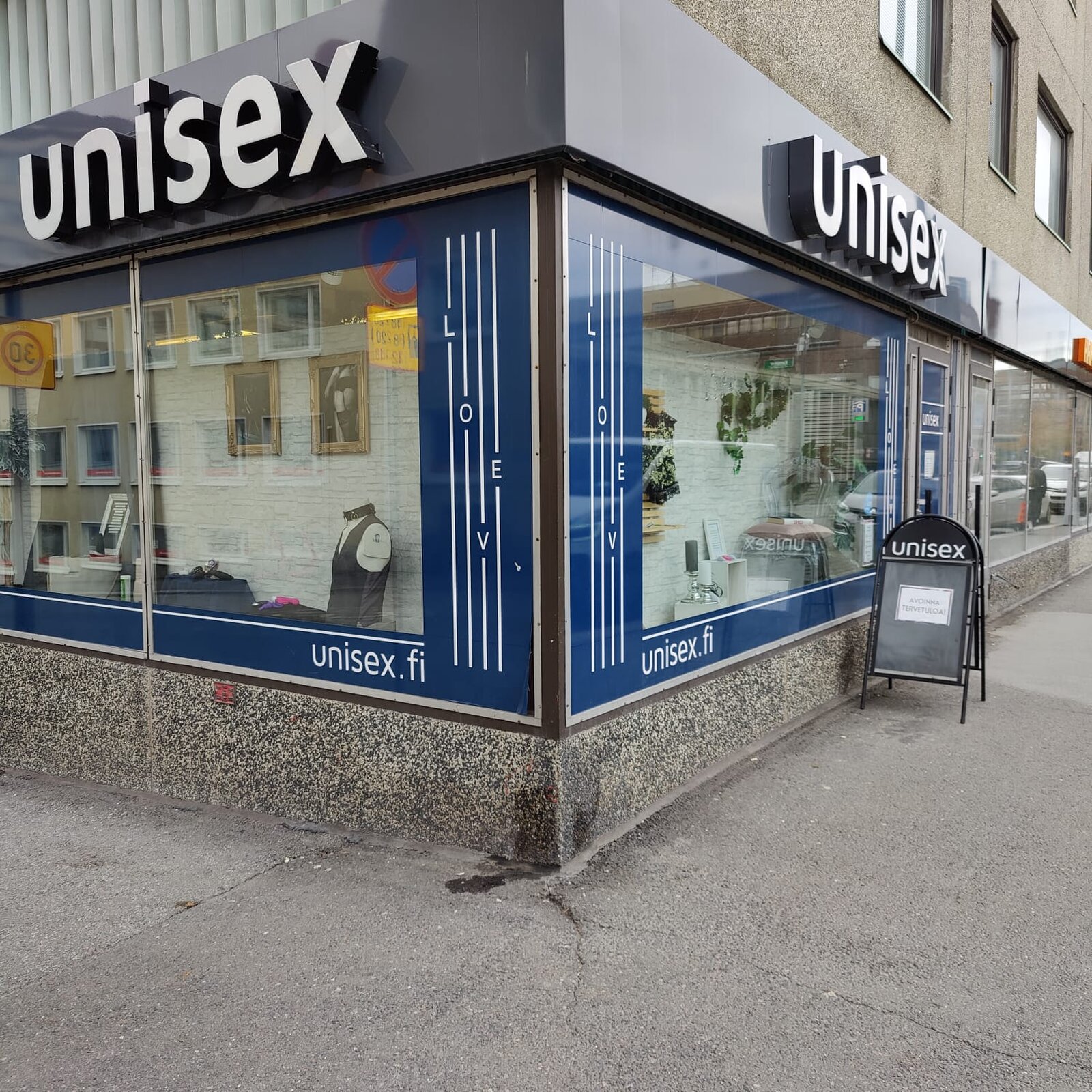 Corner shop front on the street in Tampere, with the Unisex lettering above the windows and a sandwich board by the door