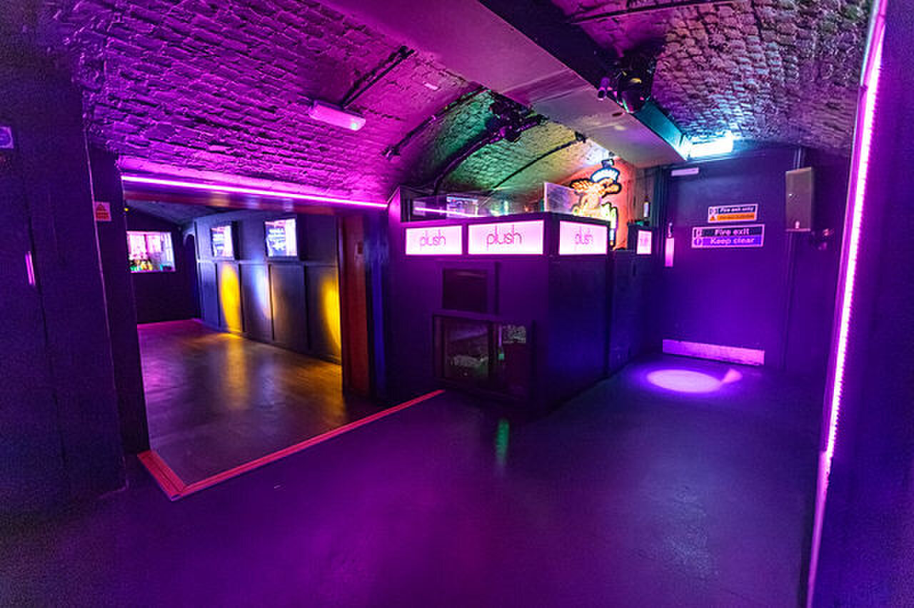 The edge of the dance floor, with a counter carrying the Plush name in lights.