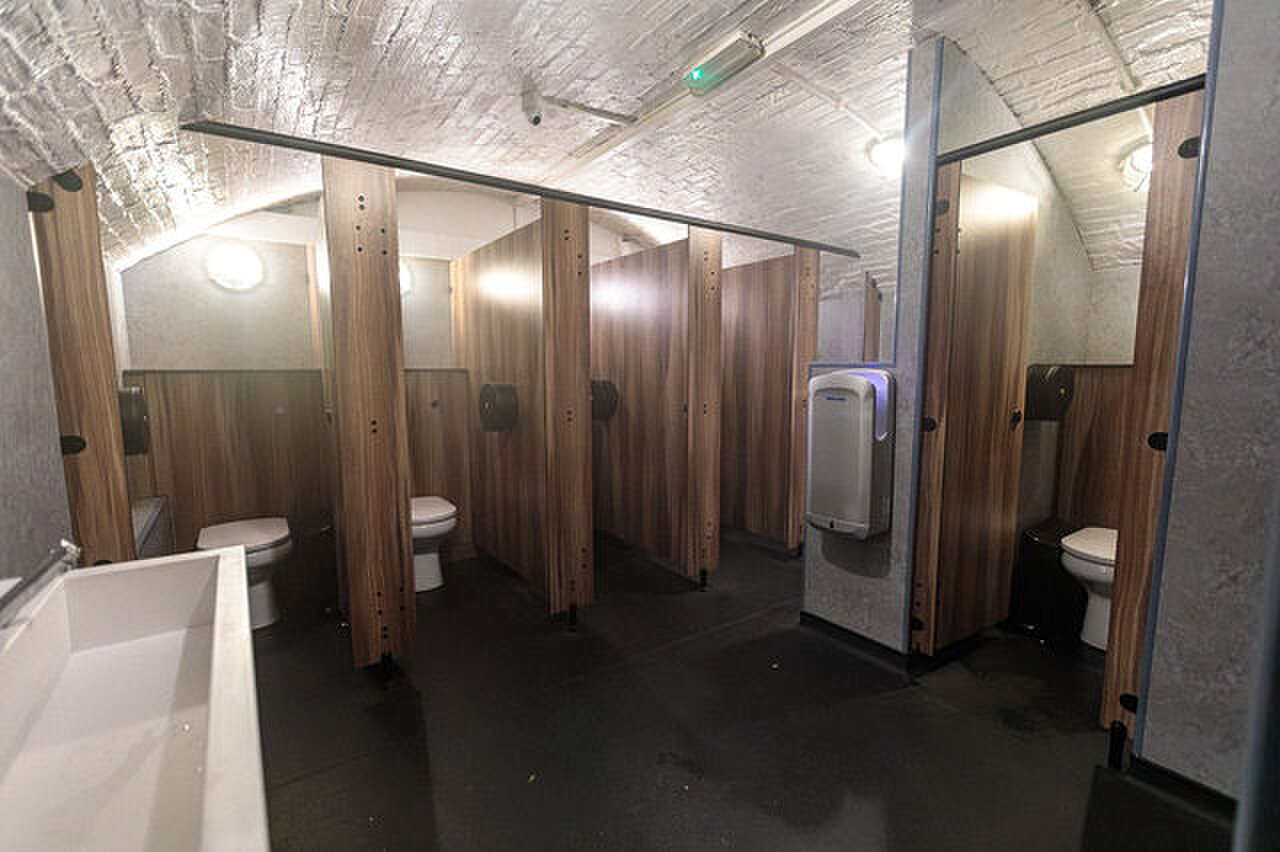 The toilets: a row of wood-panelled cubicles under a whitewashed brick vault.