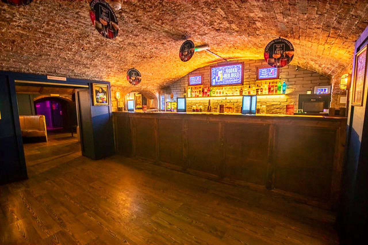 The front bar under a brick vault, its counter lit from the back shelves.