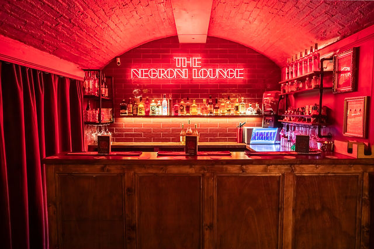 The Negroni Lounge: a cocktail bar in red light under its own neon sign.