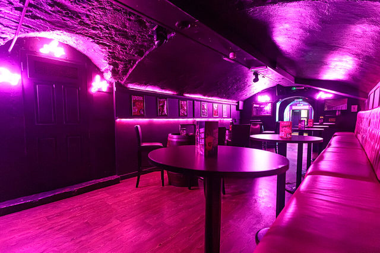 The pink room: high tables and a long padded bench under a rough stone vault.