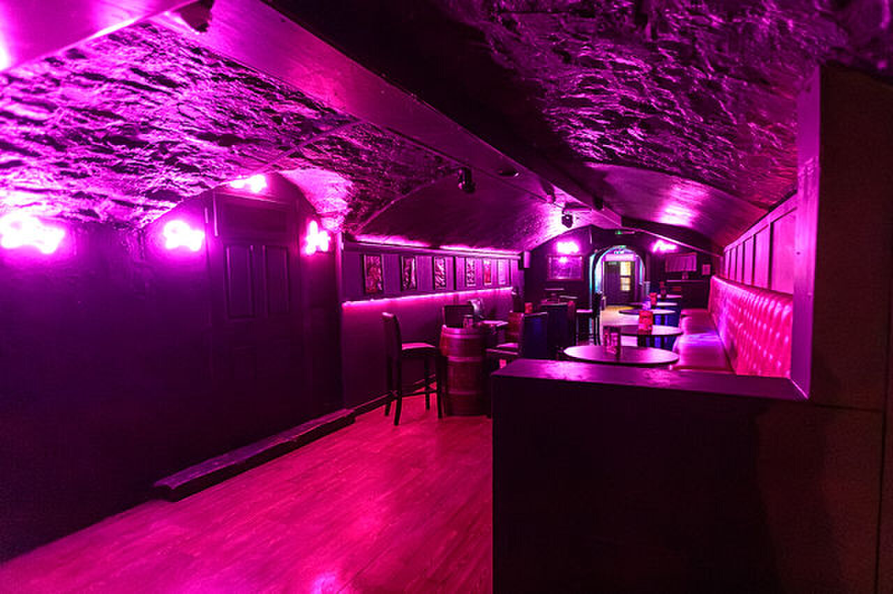 The pink room seen from the side, with barrel tables and an archway at the far end.