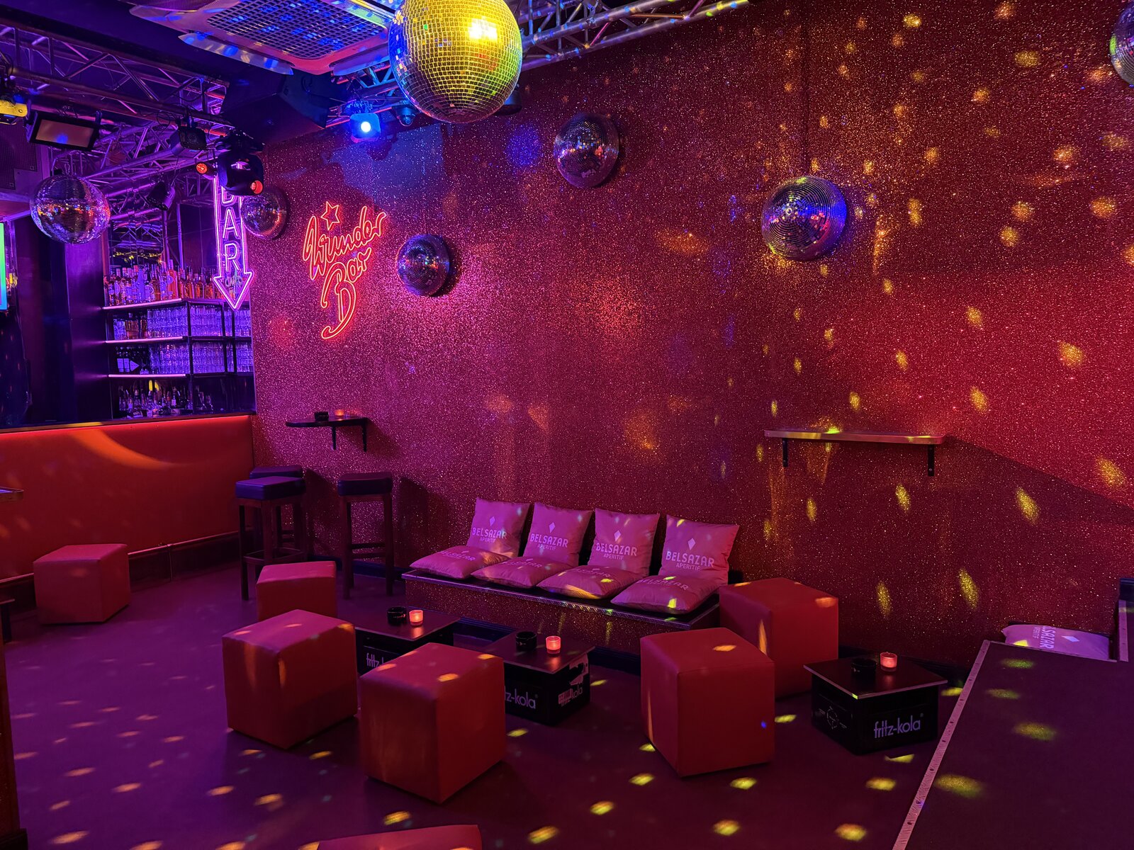 A lounge corner by the glitter wall, with cushions, cube seats and light spots from the disco balls
