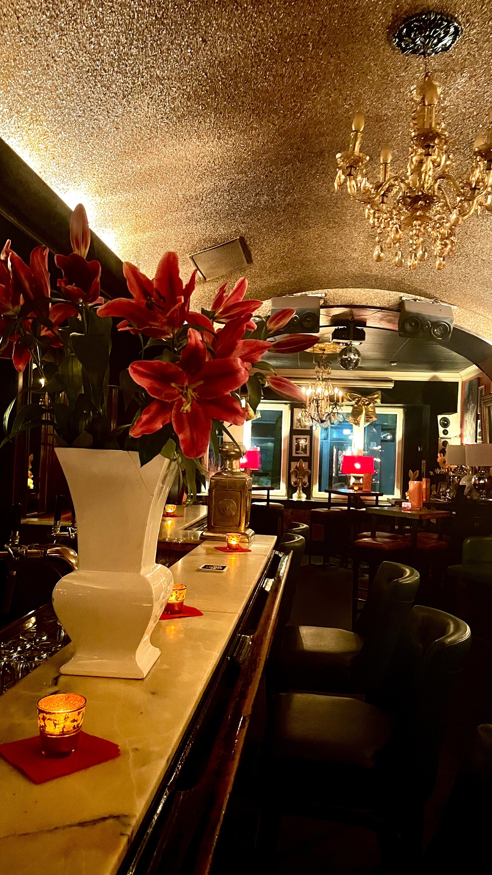 Fresh lilies on the marble bar counter, beneath the glittering vaulted ceiling and its chandeliers.