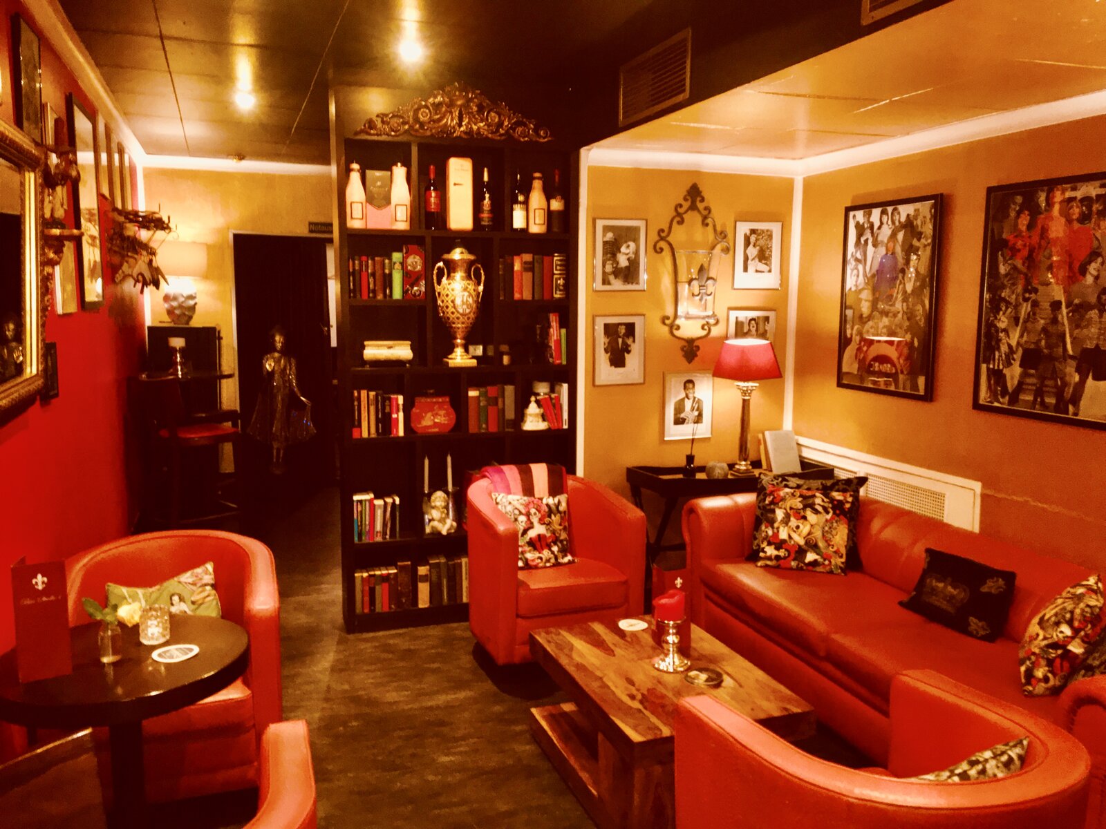 A seating area with rust-orange leather armchairs and a sofa around a black bookshelf.