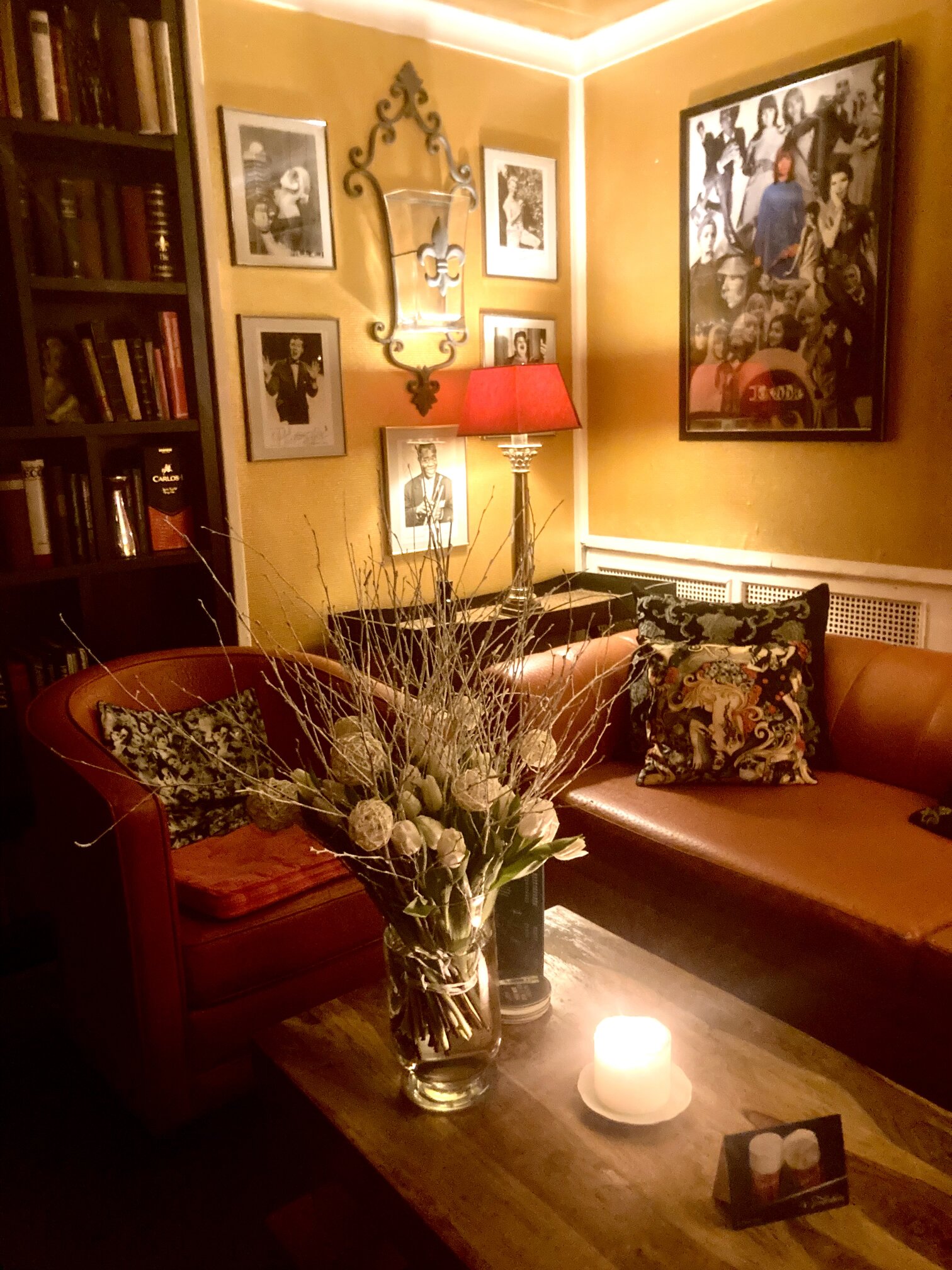 A reading corner with leather sofas, a bookshelf and a coffee table arrangement of dried flowers.