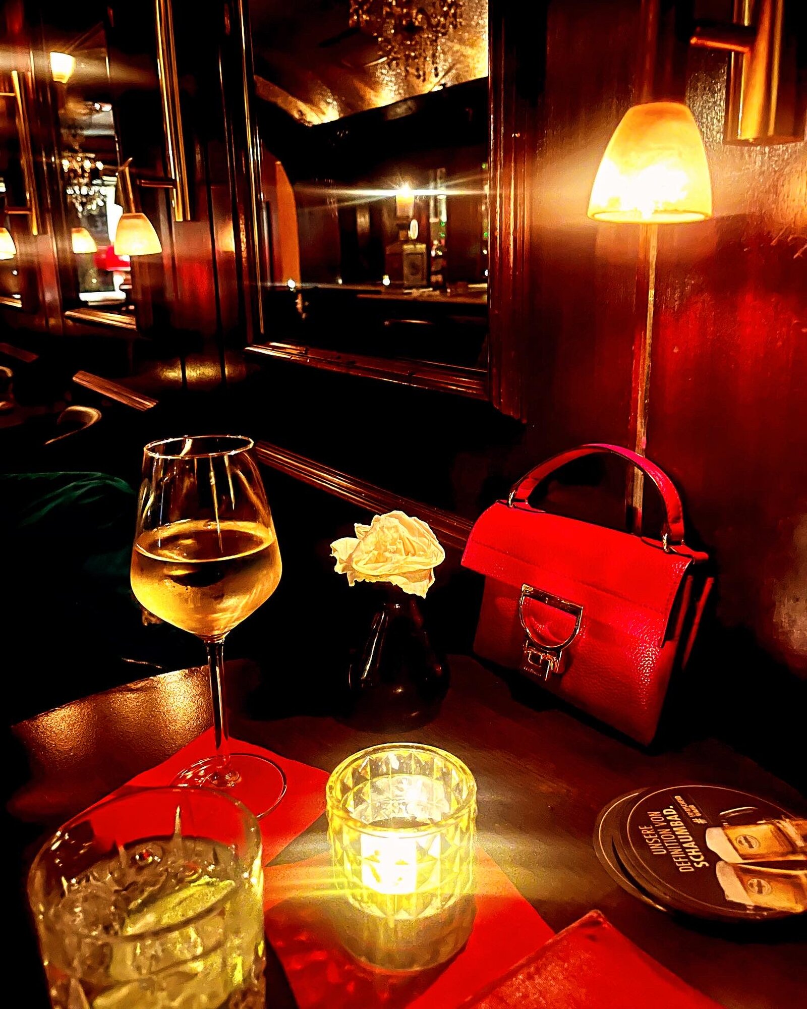 A glass of wine and a gin and tonic on a candlelit table.